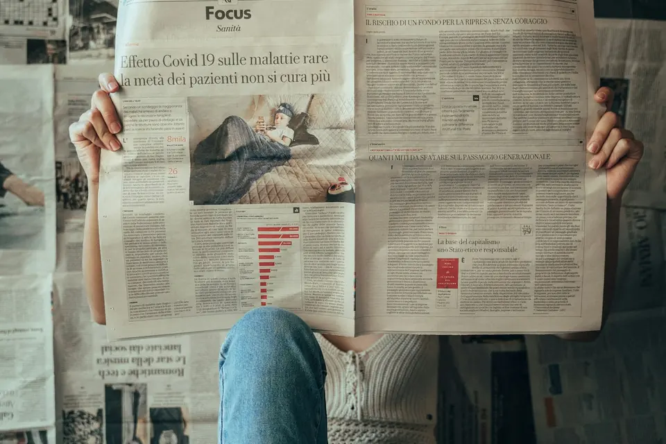 Una persona legge un quotidiano seduta sul pavimento