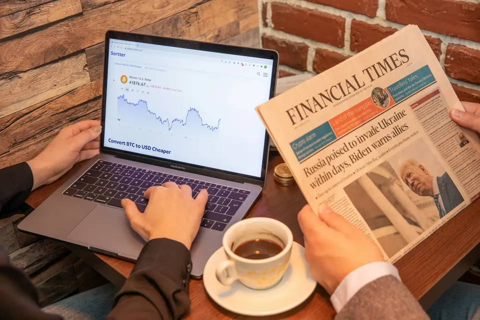 Computer con grafico finanziario, giornale e caffè su un tavolo